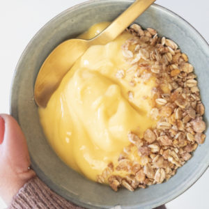 Mango proteine smoothie met granola en hand